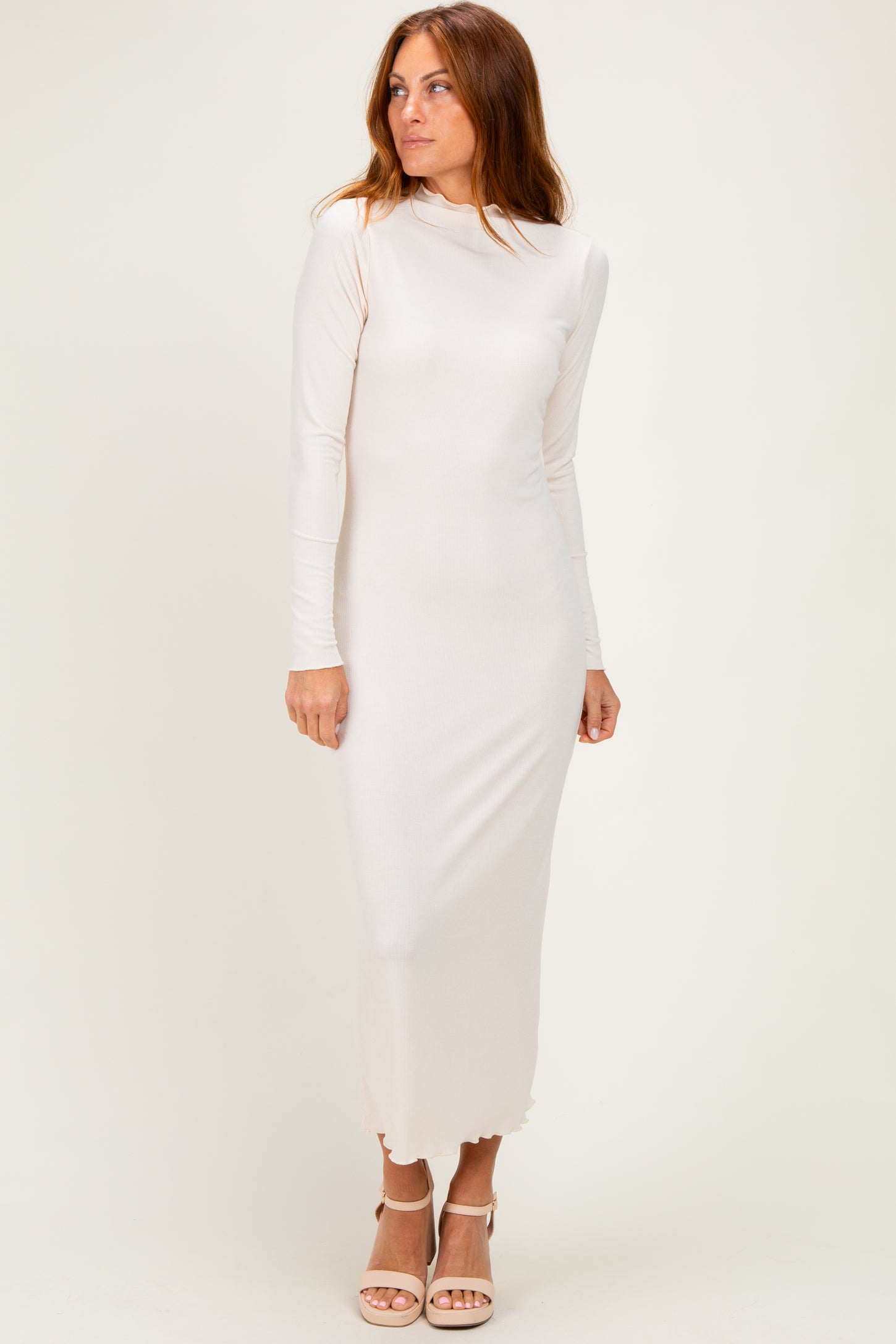 woman wearing a light beige long sleeve midi dress with a fitted silhouette and a slightly frayed hem
