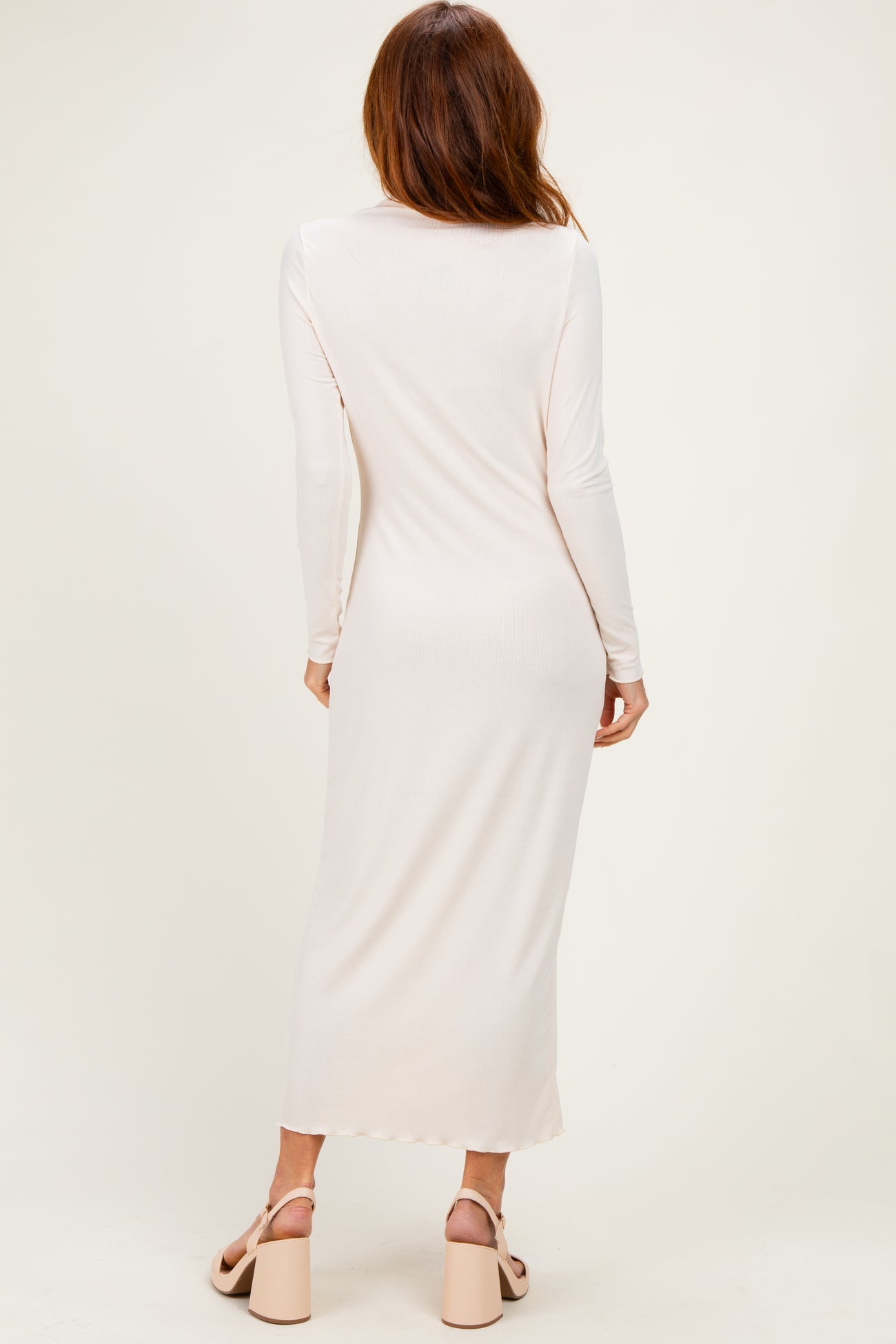 woman wearing a long sleeve light pink maxi dress from the back, paired with chunky heeled sandals