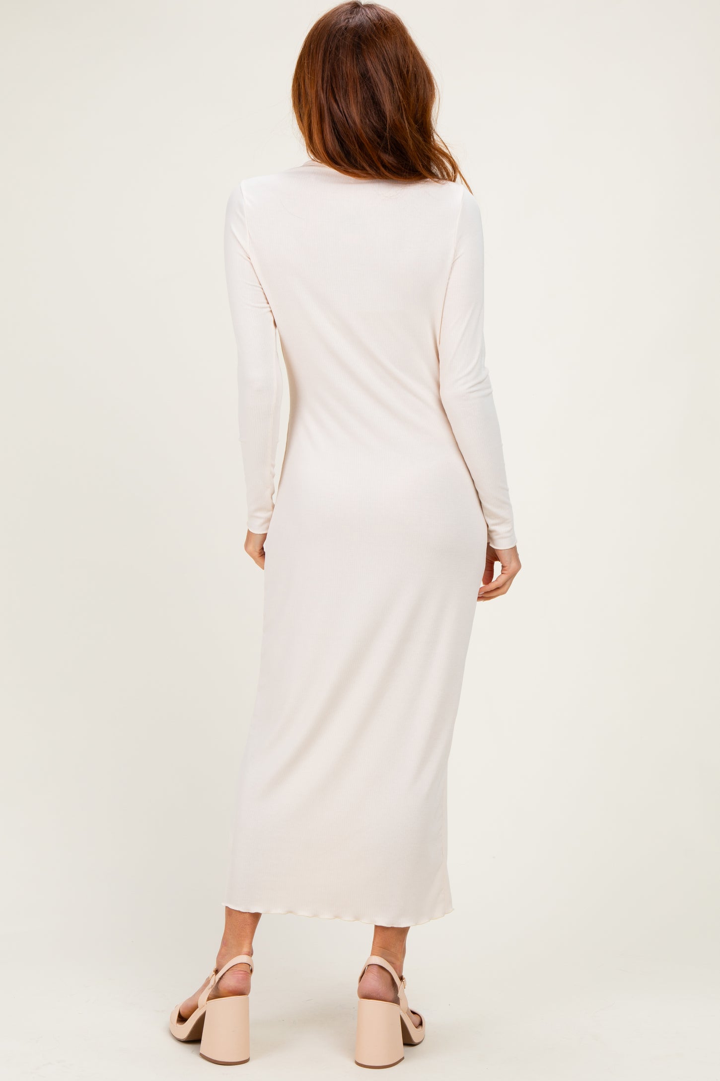 woman wearing a long sleeve light pink maxi dress from the back, paired with chunky heeled sandals