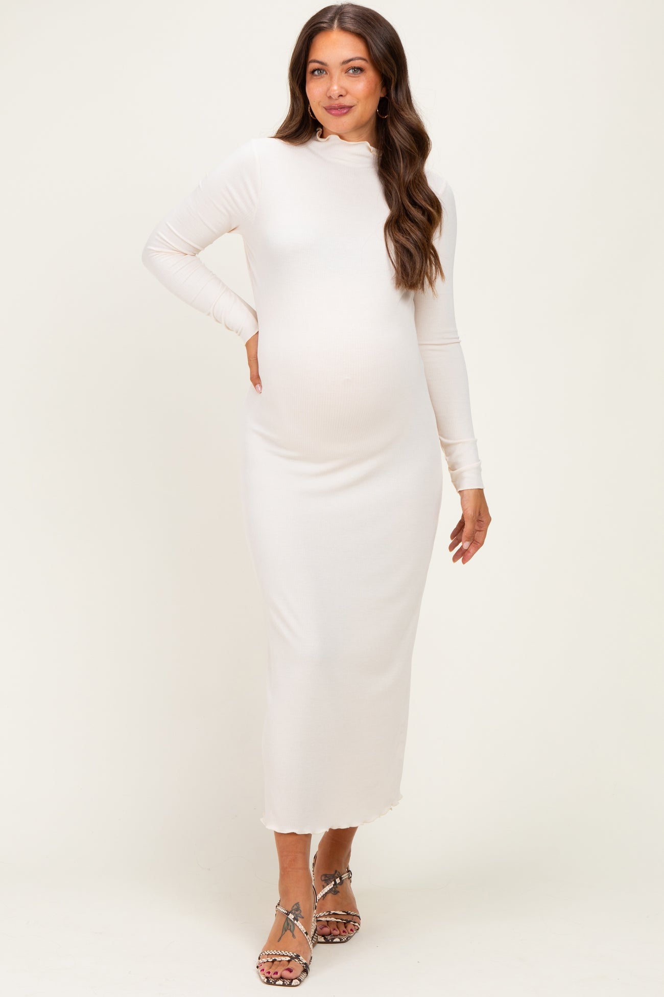 woman wearing a fitted white long sleeve maternity dress with a mock neck and a visible baby bump