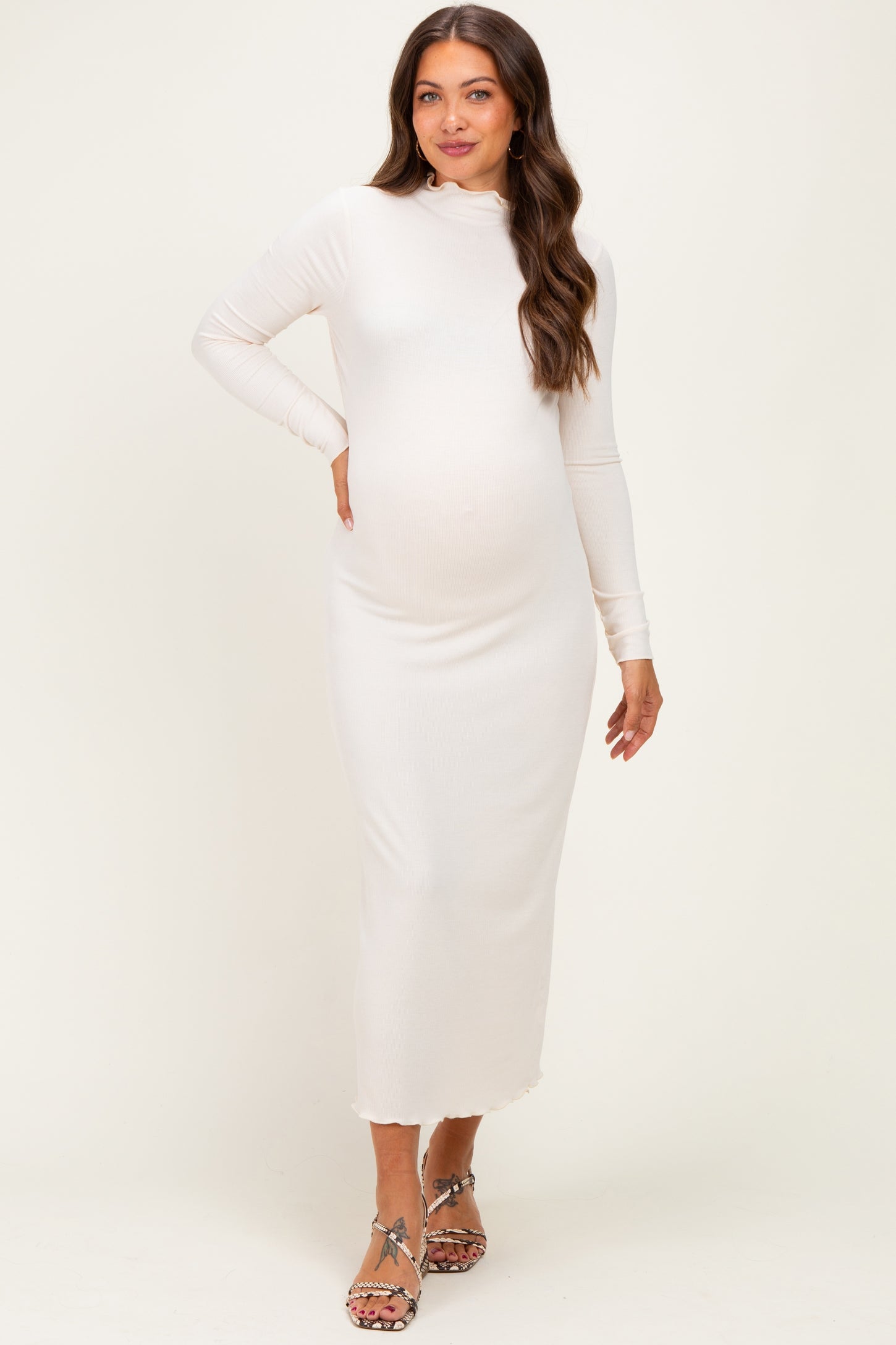woman wearing a fitted white long sleeve maternity dress with a mock neck and a visible baby bump