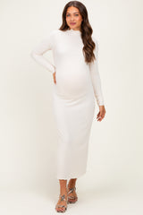 woman wearing a fitted white long sleeve maternity dress with a mock neck and a visible baby bump