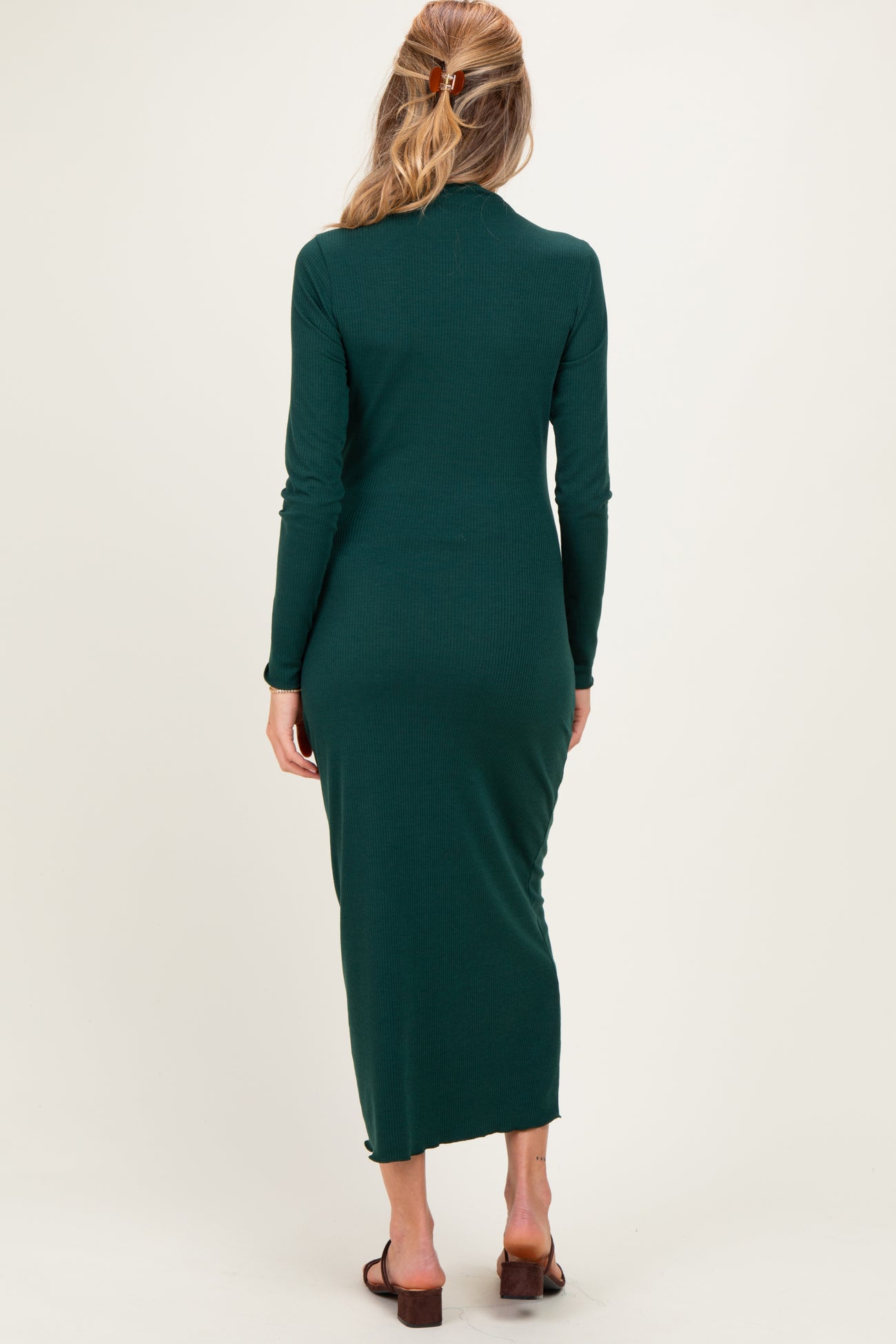 woman wearing a dark green long sleeve maternity dress with a form-fitting silhouette