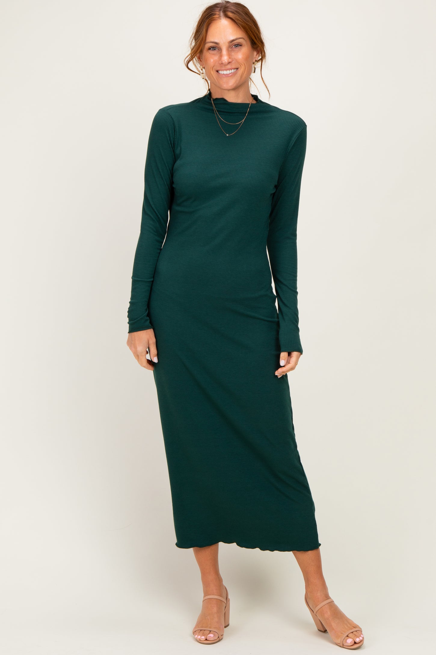 woman wearing a dark green long sleeve ribbed maxi dress and nude heels