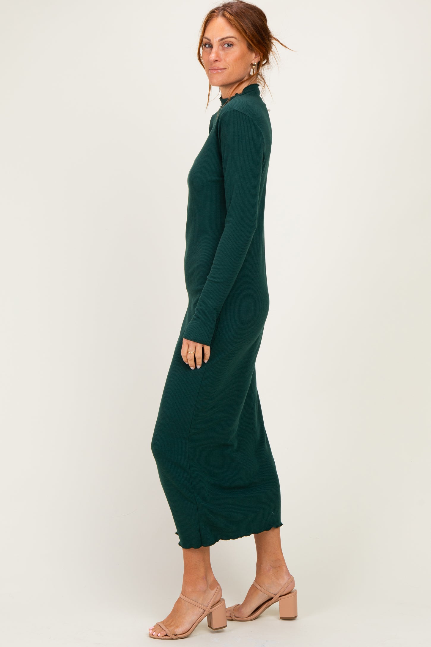 woman wearing a dark green long sleeve midi dress with a scalloped hem and styled with light brown sandals