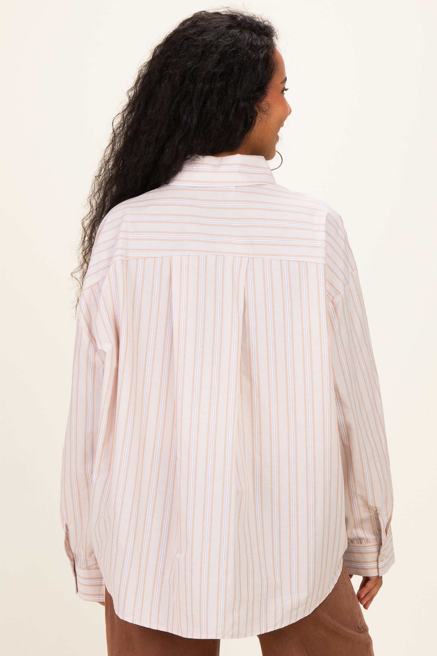 woman wearing a striped maternity button-up shirt in light colors, showing the back of the garment
