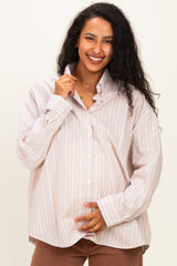 woman wearing a striped oversized maternity shirt and gently holding her baby bump
