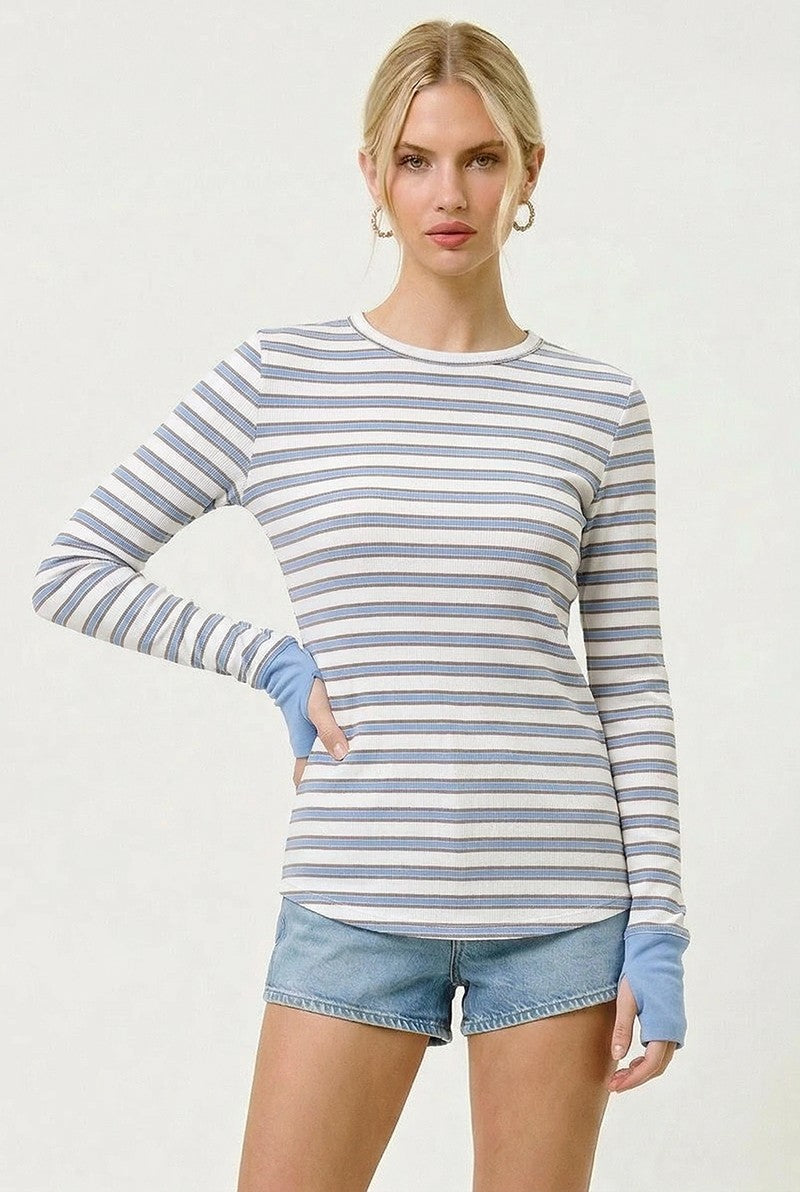 woman wearing a striped long sleeve top in blue and white with contrasting blue cuffs, paired with denim shorts