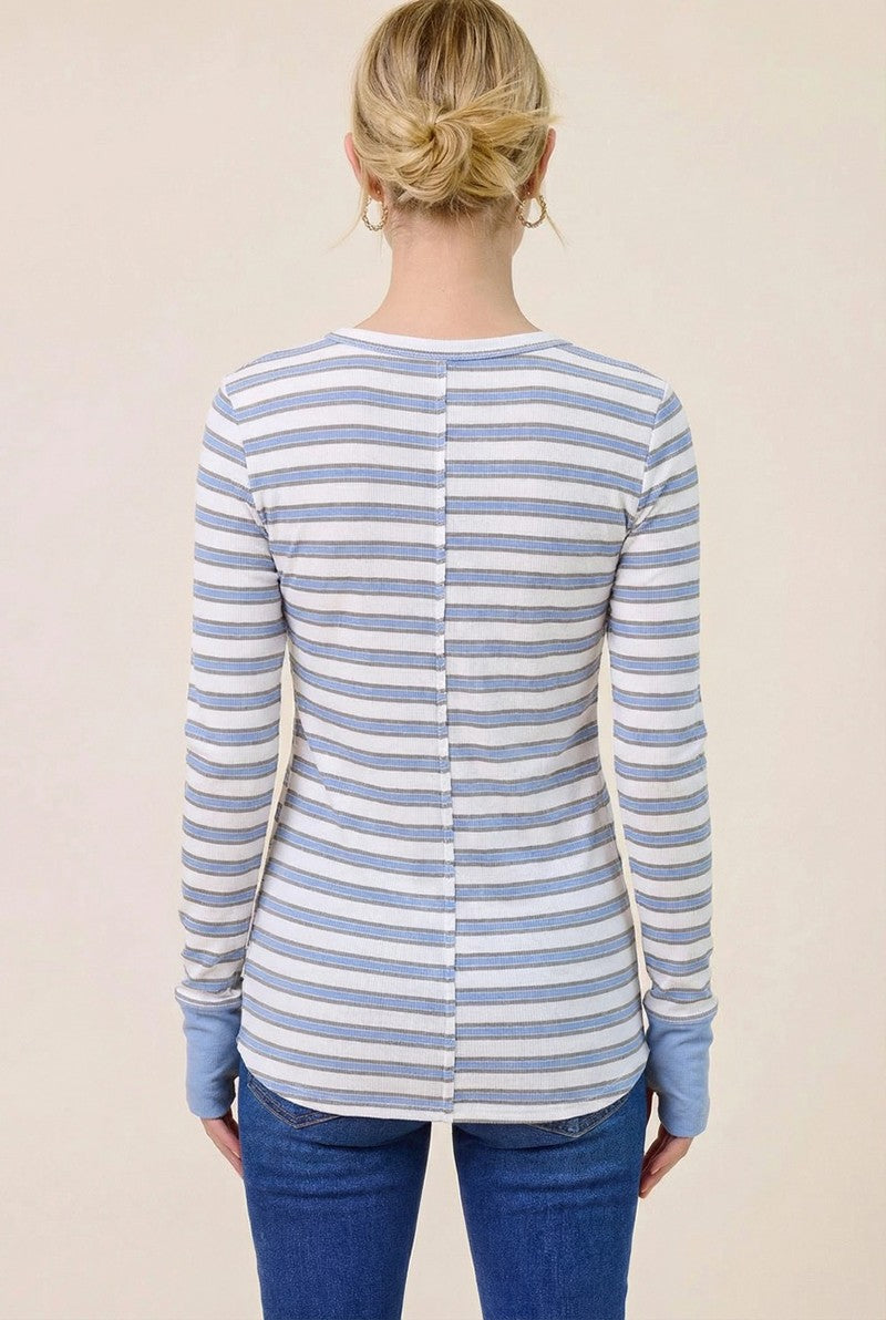 woman wearing a white and blue striped long sleeve shirt with a buttoned back and blue cuffs, seen from the back