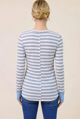 woman wearing a white and blue striped long sleeve shirt with a buttoned back and blue cuffs, seen from the back
