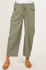 woman wearing olive green striped maternity pants with side pockets and an elastic waistband