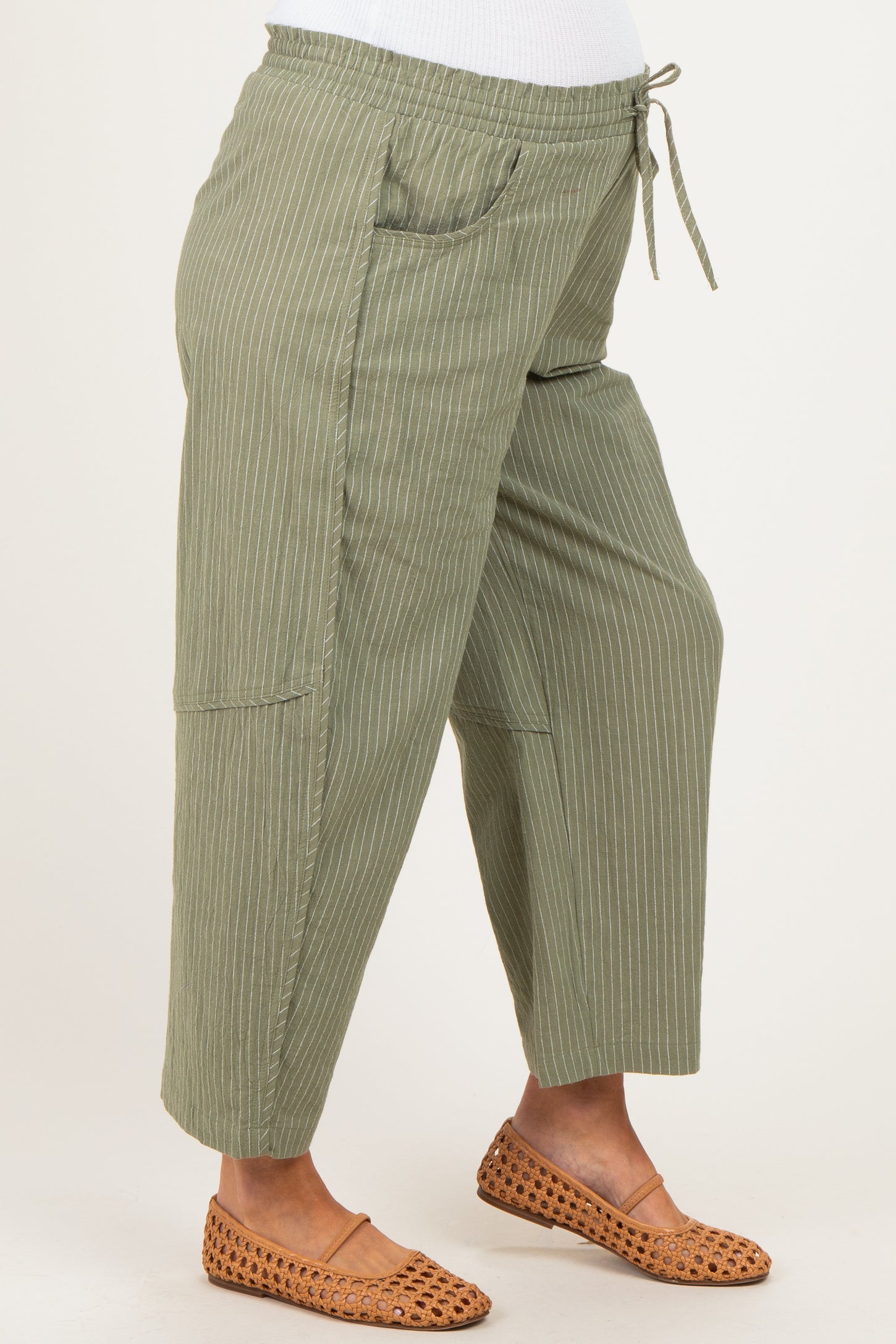 maternity wear olive green striped pants with a drawstring waist and pockets, model showing her baby bump