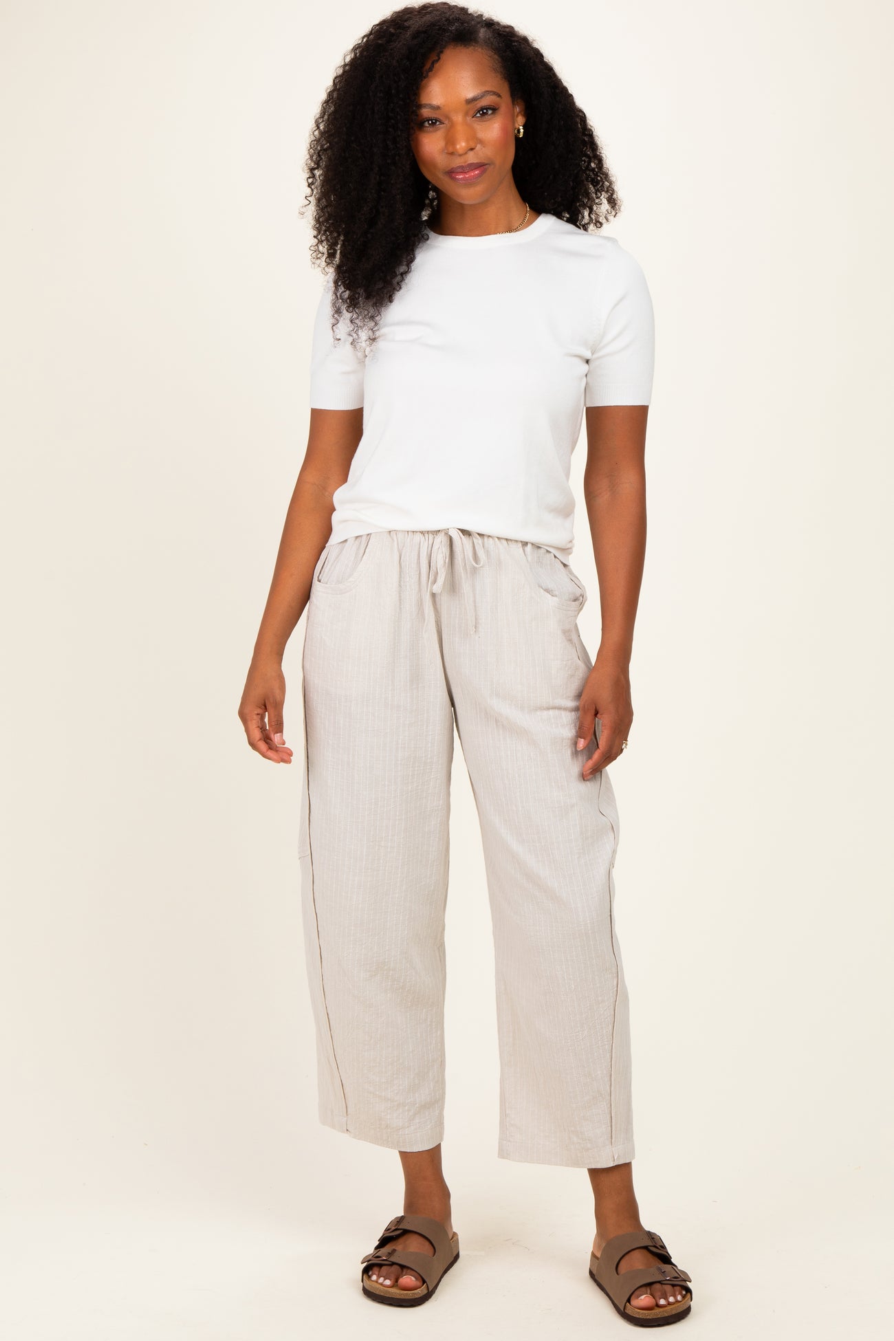 woman wearing a white short sleeve top and light beige wide-leg pants with side pockets and a relaxed fit