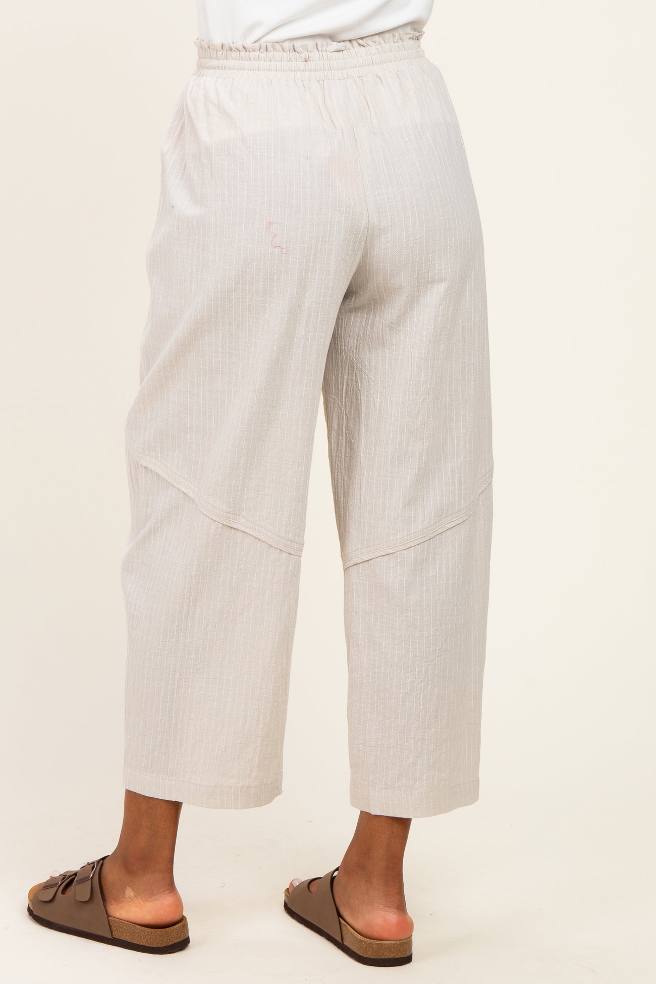 woman wearing light beige wide-leg cropped pants with an elastic waistband and subtle textured pattern