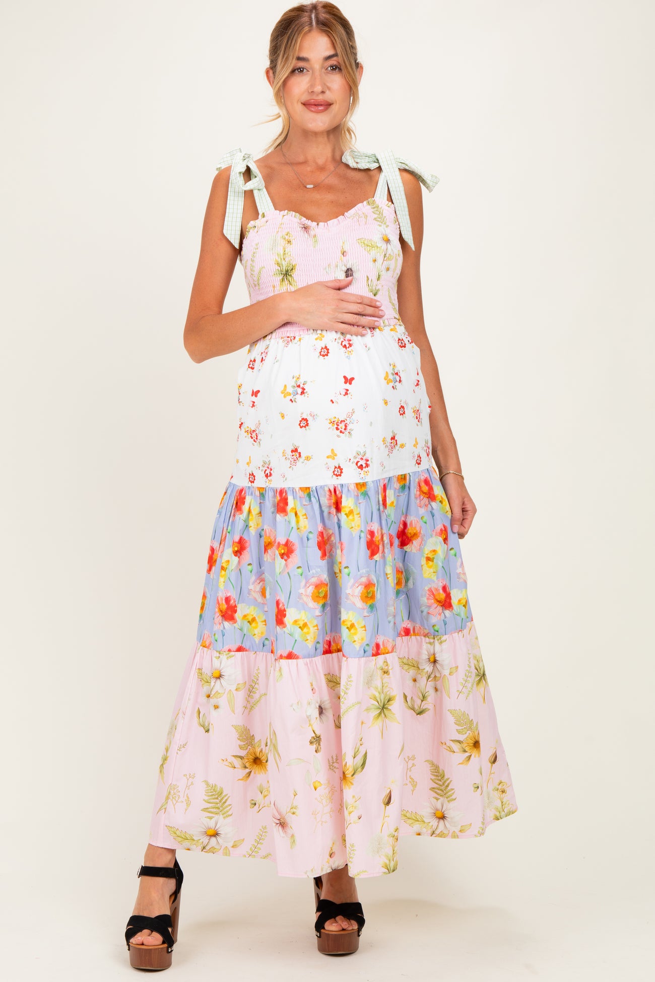 woman wearing a colorful floral maternity maxi dress with adjustable straps and a baby bump