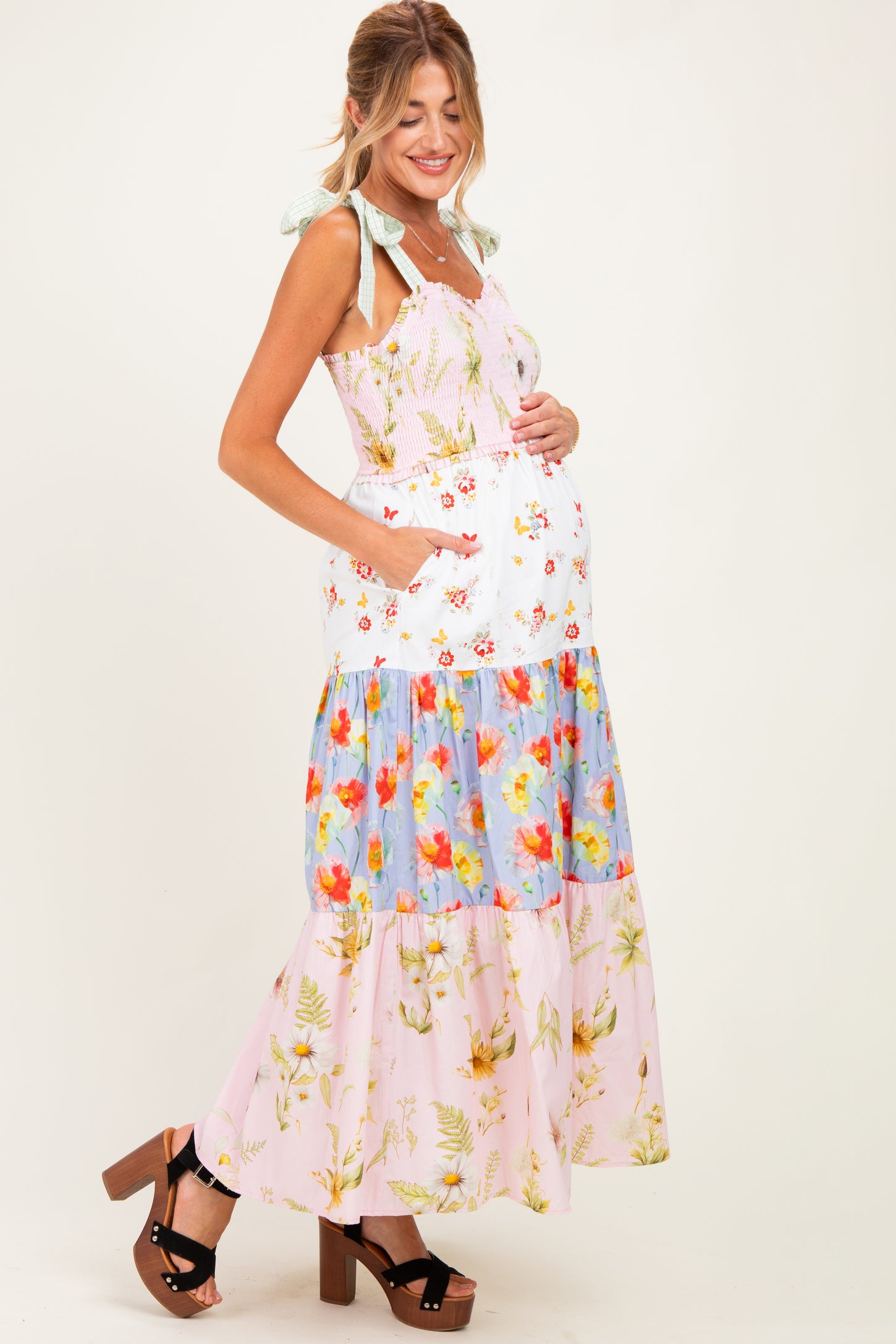 woman wearing a floral maternity maxi dress with tiered design and bow straps, showing her baby bump