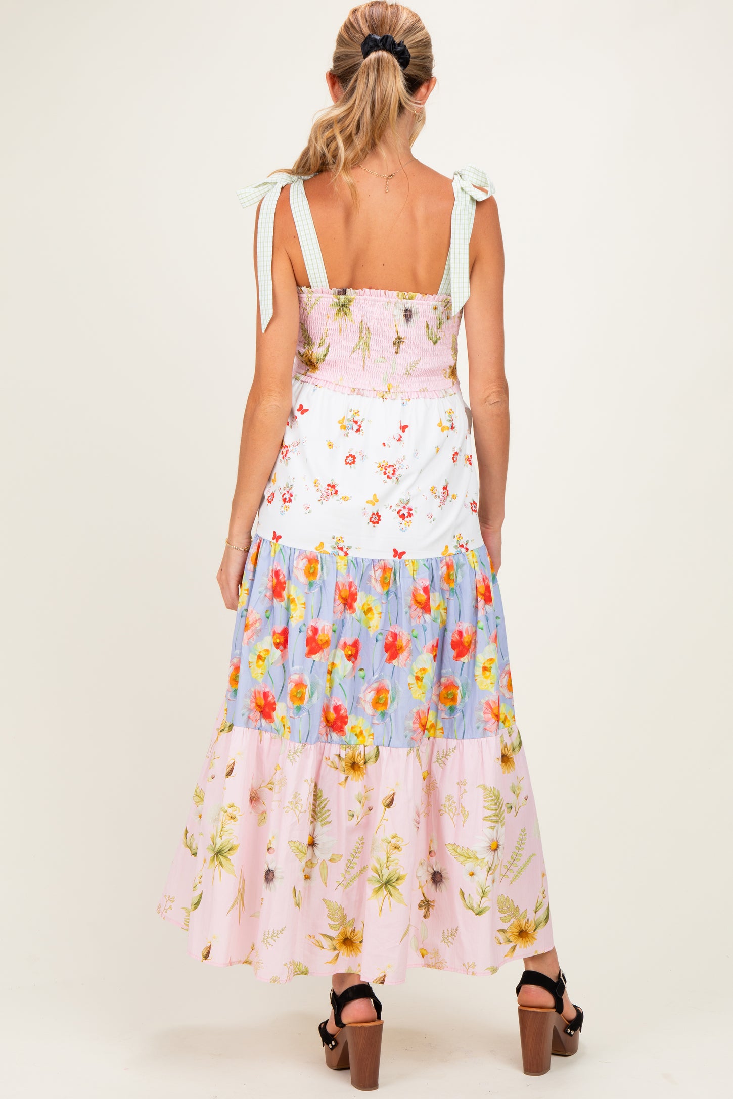 woman wearing a floral maternity maxi dress with a smocked bodice and adjustable straps, showing a baby bump from the back