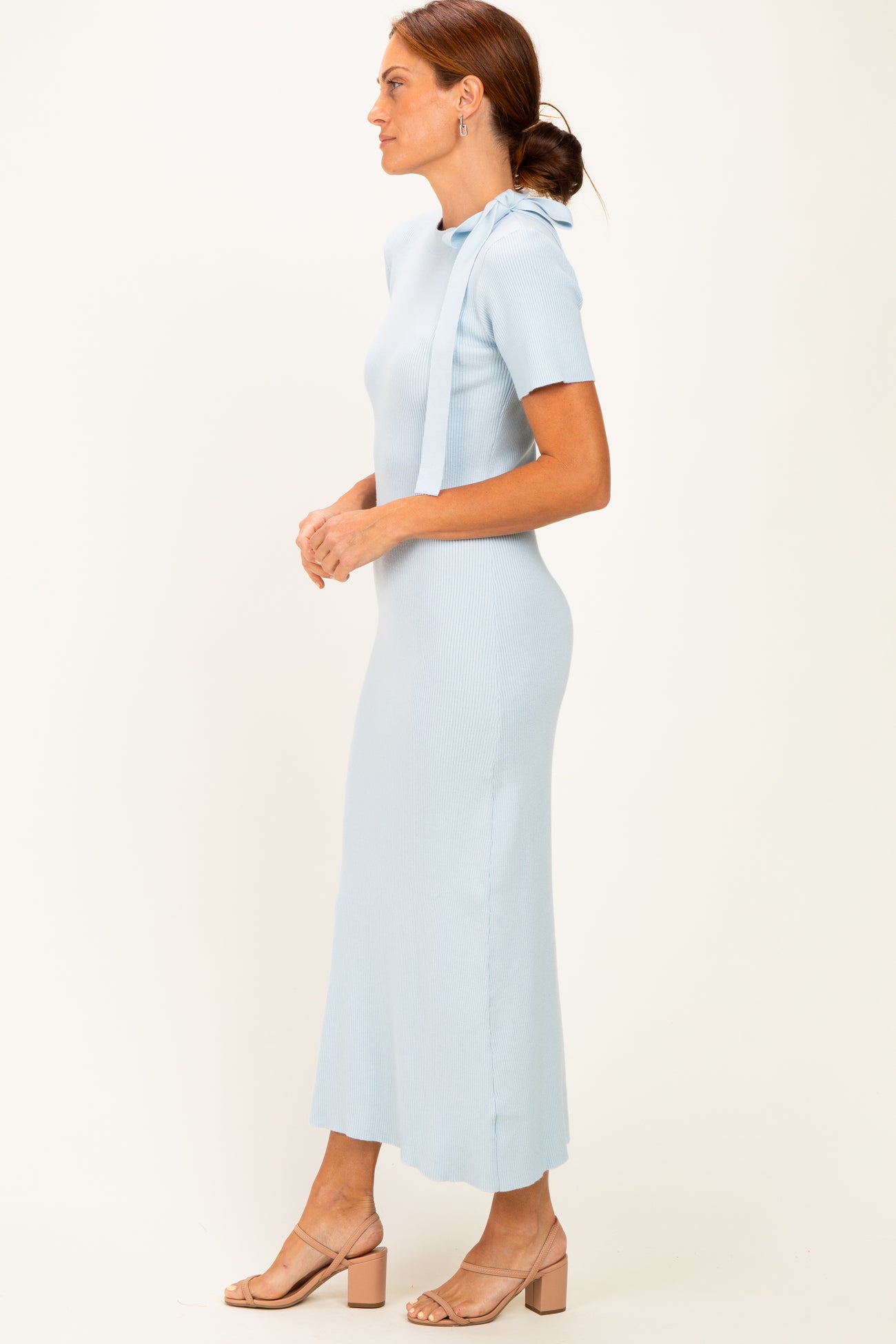 woman wearing a light blue ribbed knit maxi dress with short sleeves and side slits, standing sideways
