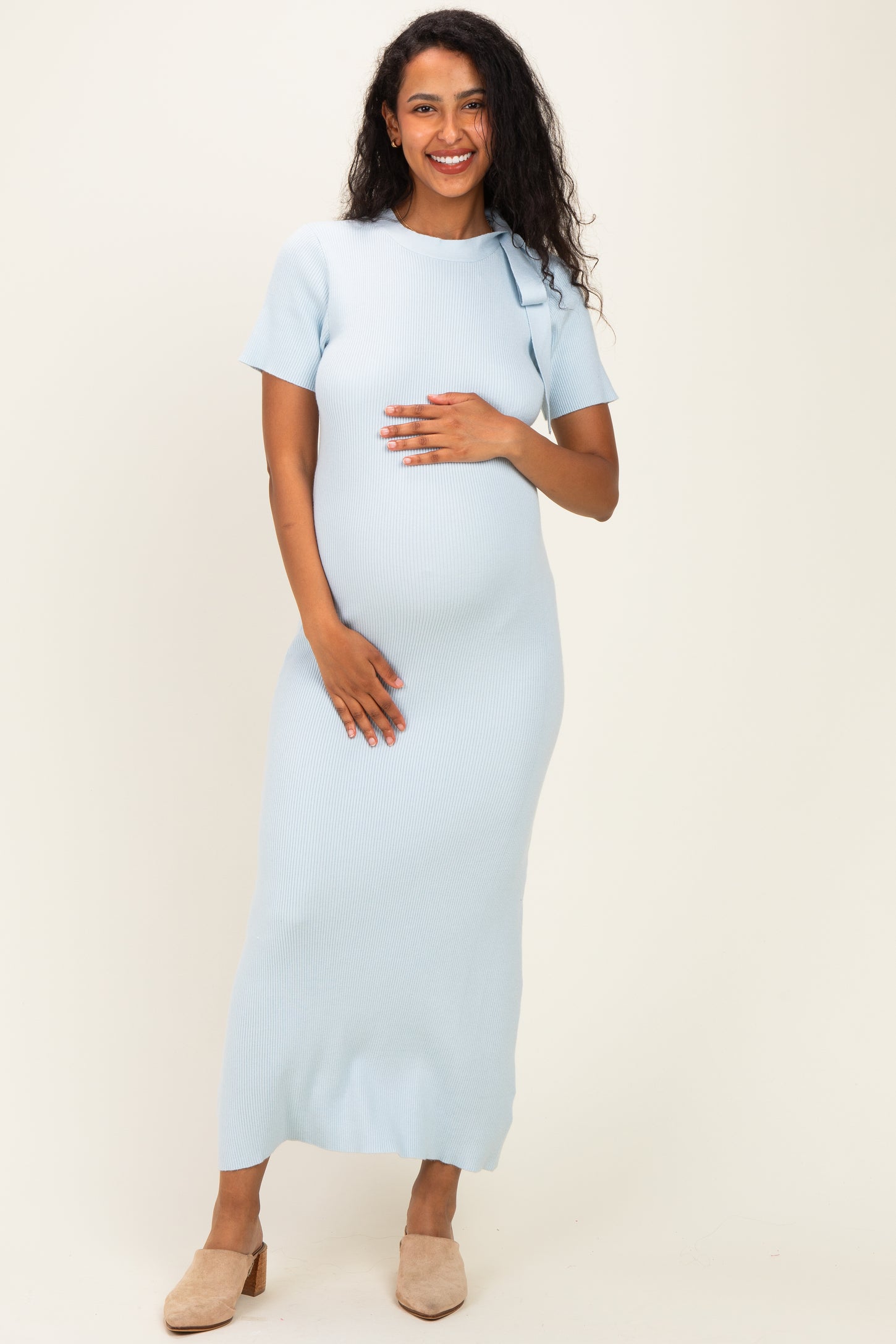 woman wearing a light blue ribbed maternity dress and holding her baby bump