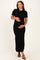 woman wearing a black ribbed maternity dress with a bow detail, holding her baby bump