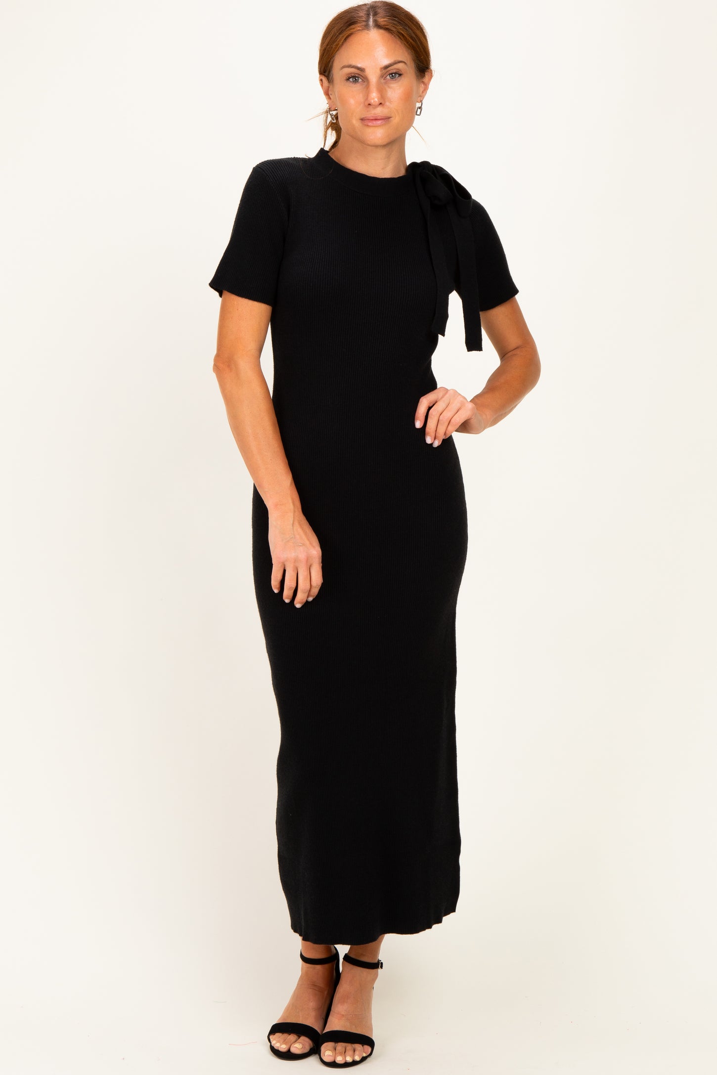 woman wearing a black ribbed knit maxi dress with short sleeves and a bow detail on the shoulder