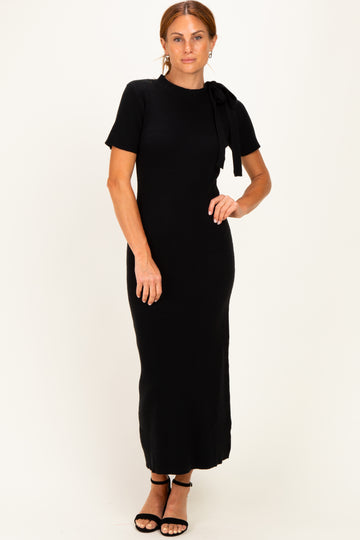 woman wearing a black ribbed knit maxi dress with short sleeves and a bow detail on the shoulder