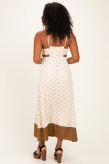 woman wearing a white midi dress with brown polka dots and a brown bottom hem, showing the back view