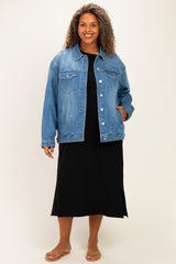 woman wearing a relaxed fit light wash denim jacket over a black midi dress, standing with hands in pockets