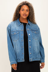 woman wearing a light blue oversized denim jacket with front pockets and silver buttons over a black dress