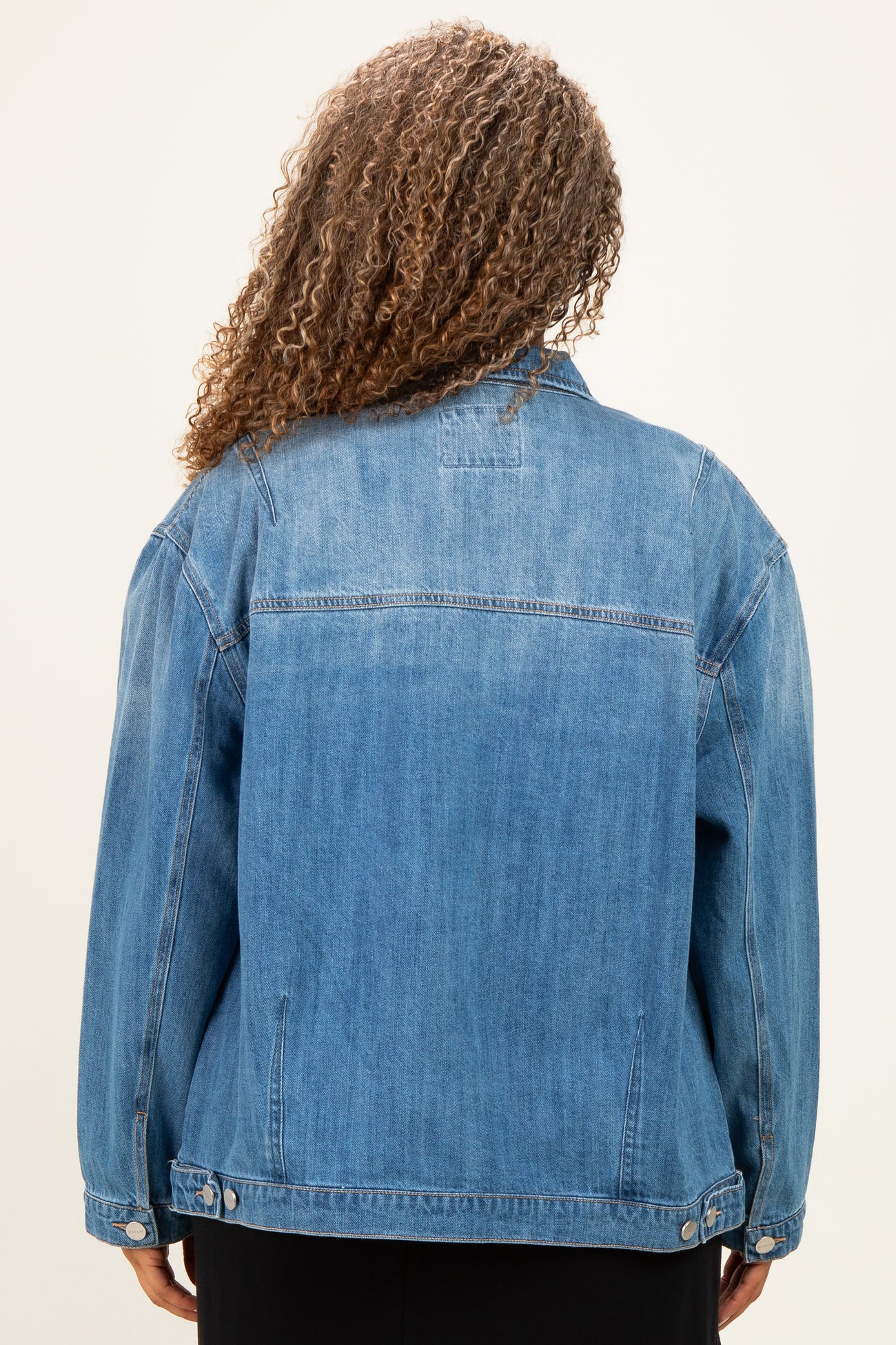 woman wearing a light blue plus size denim jacket, view from the back