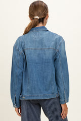 woman wearing a light blue denim maternity jacket, seen from the back with long sleeves and relaxed fit