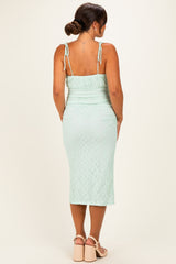 woman wearing a mint green maternity dress with adjustable straps and a fitted silhouette, showing her baby bump from the back