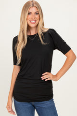 woman wearing a black short sleeve top with gathered sides and a relaxed fit, paired with blue jeans