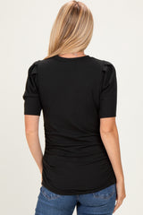 woman wearing a black ribbed top with puffed sleeves and gathered side detailing, seen from the back