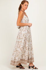 woman wearing a beige floral maxi dress with adjustable straps and a tiered hem, styled with black sandals