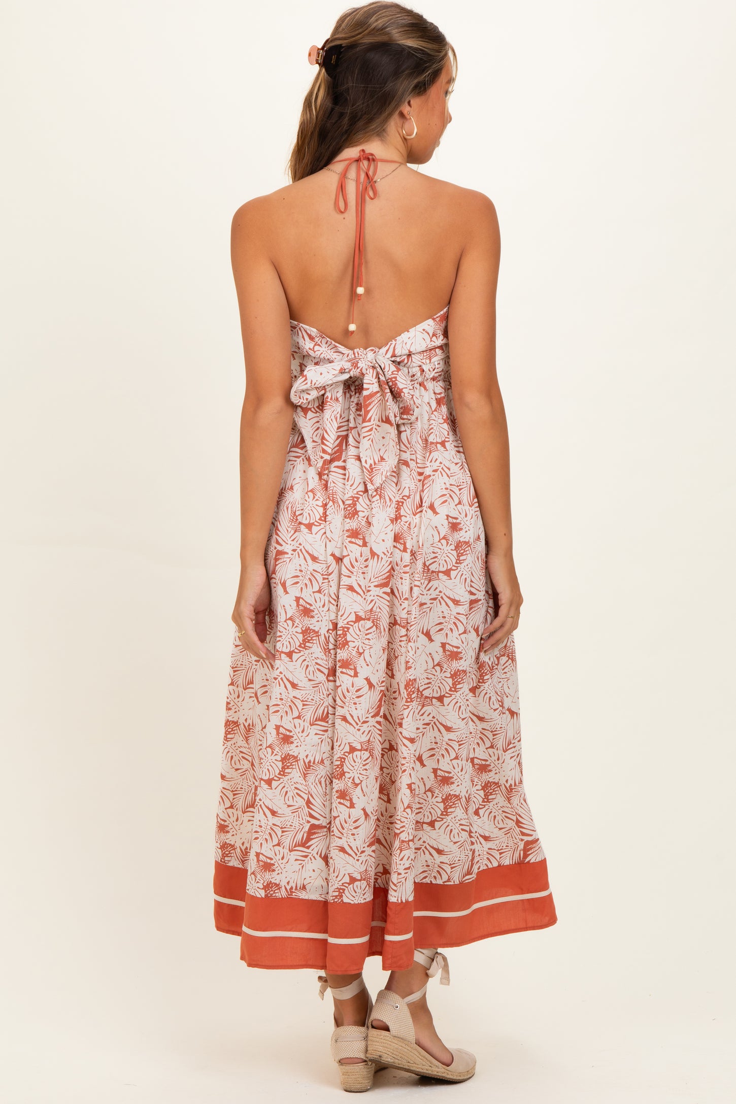 woman wearing a floral maternity maxi dress with a halter neckline and open back detail