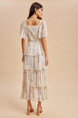 woman wearing a cream floral tiered maxi dress with puff sleeves, shown from the back