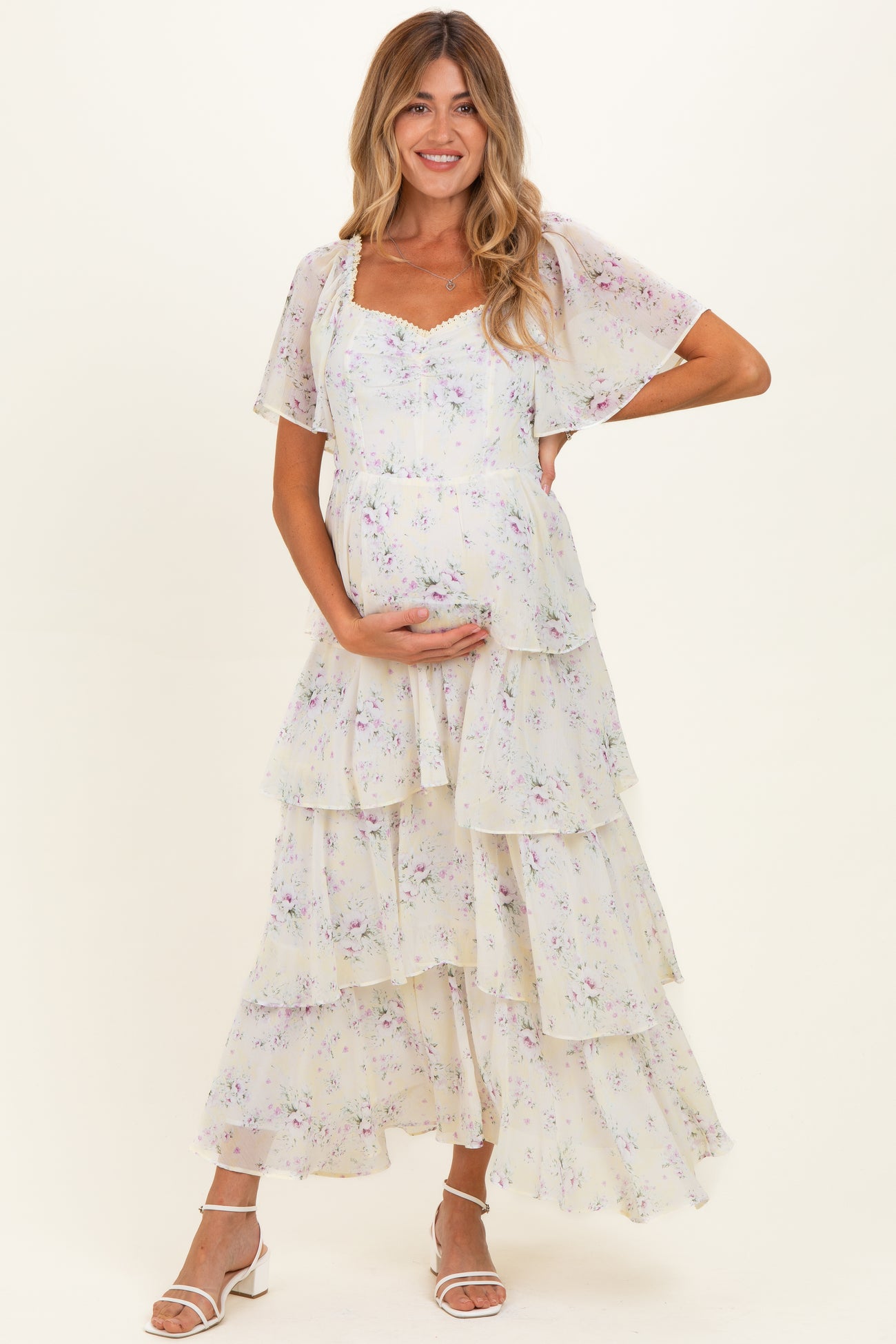 woman wearing a floral tiered maternity maxi dress and holding her baby bump