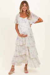 woman wearing a floral tiered maternity maxi dress and holding her baby bump