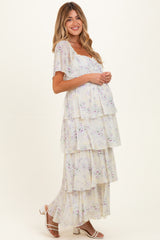 woman wearing a floral tiered maxi maternity dress with short flutter sleeves and a visible baby bump