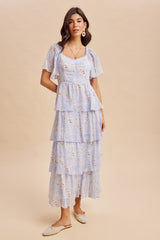 woman wearing a light blue floral tiered maxi dress with short puff sleeves and a square neckline