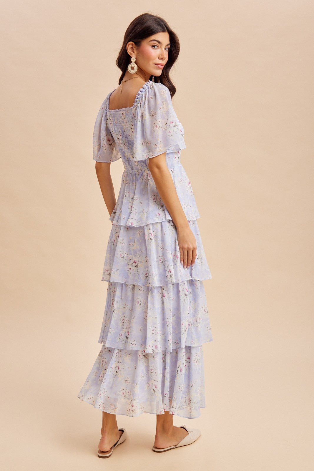 woman wearing a light purple floral tiered maxi dress with puff sleeves and a square neckline, standing sideways