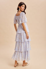 woman wearing a light purple floral tiered maxi dress with puff sleeves and a square neckline, standing sideways