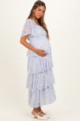 woman wearing a light blue floral maternity maxi dress with tiered layers and a visible baby bump