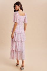 woman wearing a pink floral tiered maxi dress with short sleeves and a fitted bodice, seen from the back