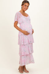 woman wearing a light pink floral maternity maxi dress and cradling her baby bump