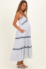 woman wearing a white and navy polka dot maternity maxi dress with spaghetti straps and pockets, showing her baby bump