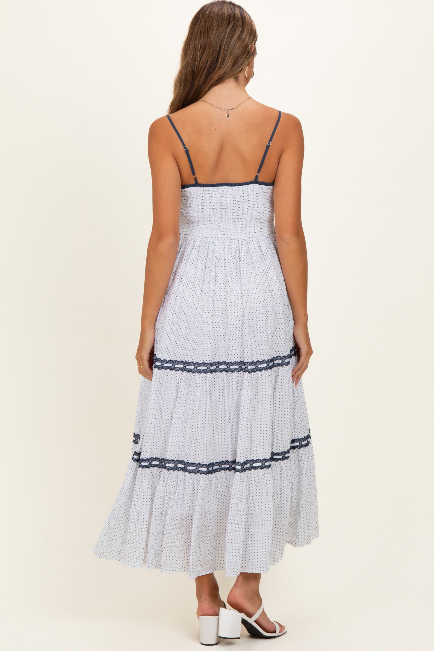 woman wearing a white maternity maxi dress with navy lace details and thin straps, showcasing a comfortable fit