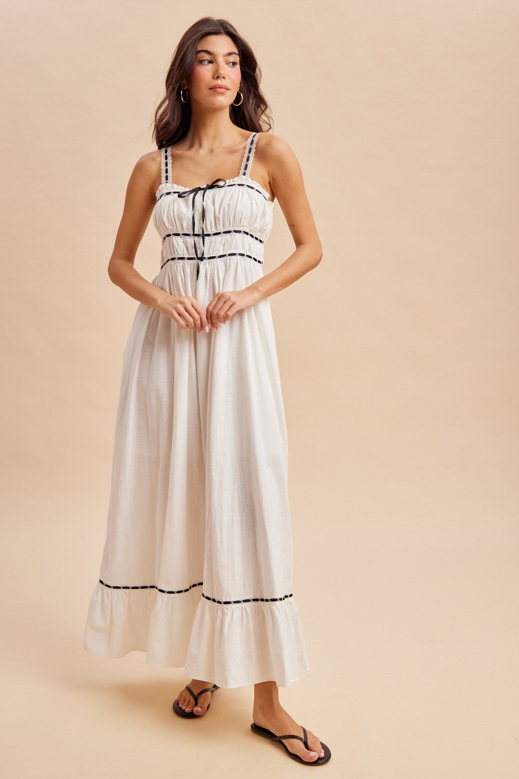 woman wearing a white maxi dress with black trim and adjustable straps