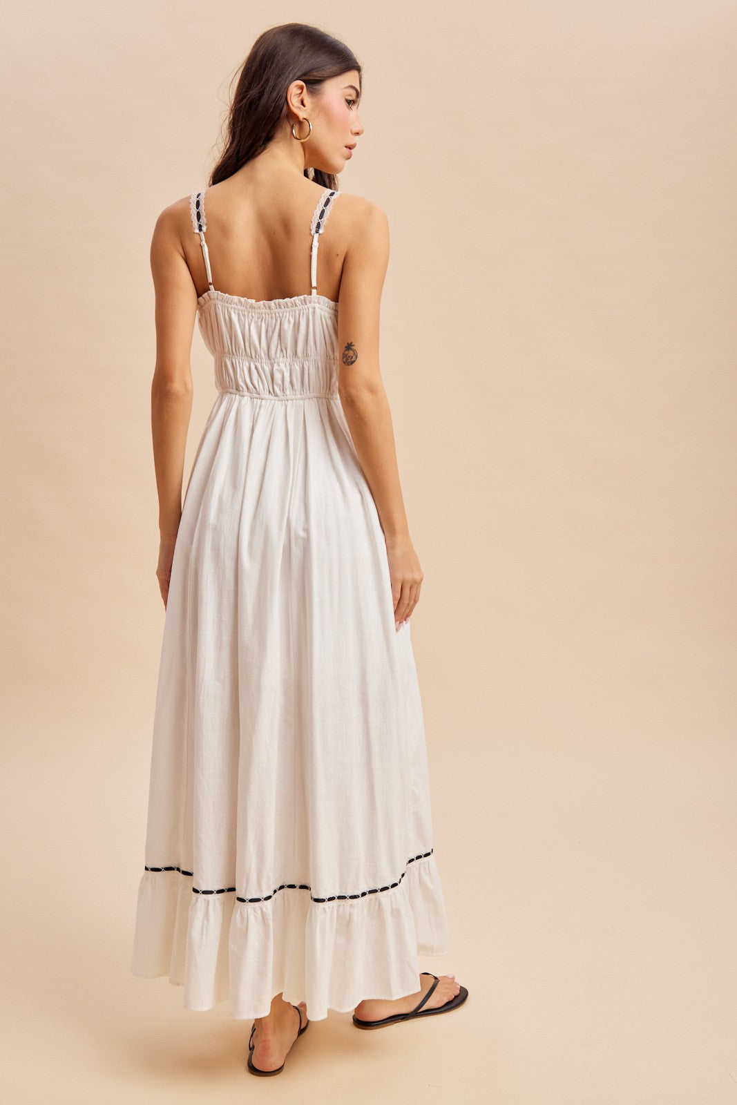 woman wearing a white maxi dress with smocked back and black detailing, viewed from the back